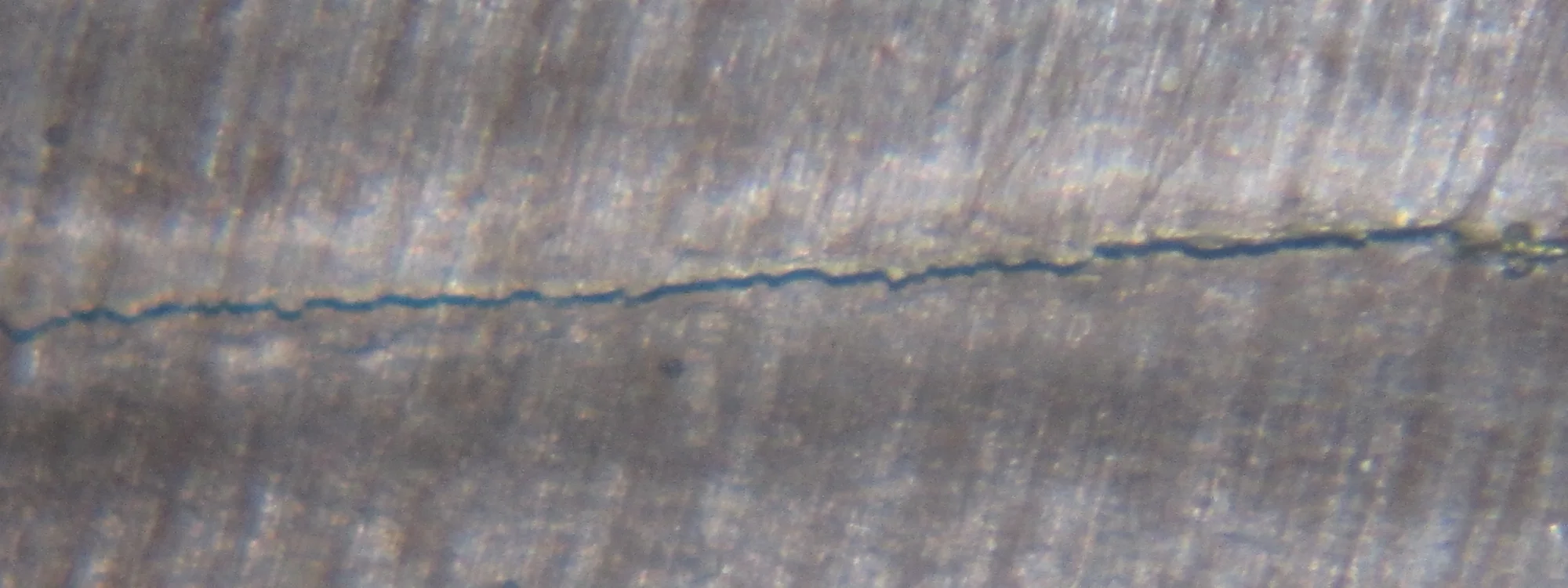 Makroaufnahme eines feinen Risses in einer Metalloberfläche
